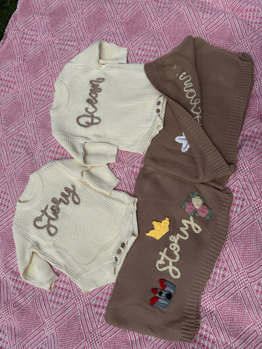 Baby rompers and matching blankets with embroidered designs on a pink textured fabric background